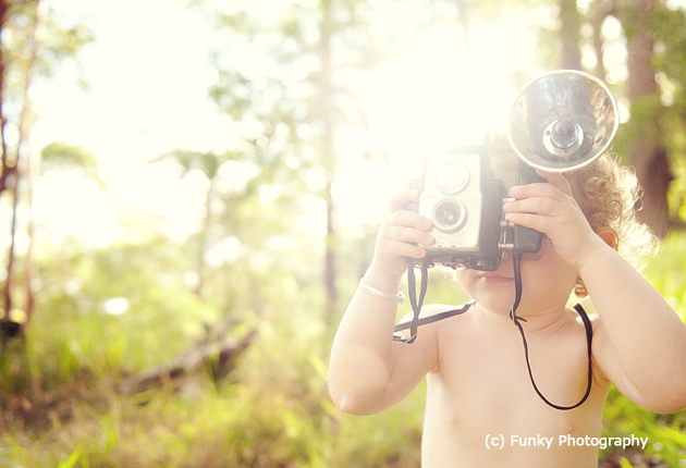 baby photography using a vintage camera as a prop and sunflare