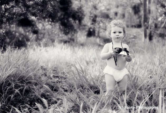 photograph of a toddler with a vintage starflex kodak camera in the woods